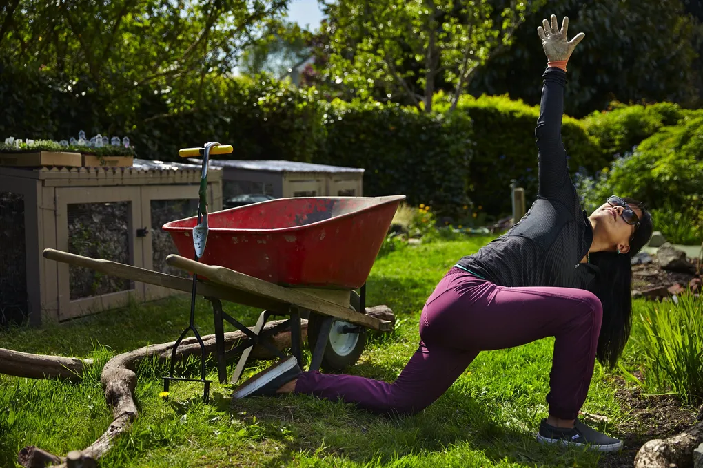 Image of a woman stretching while outside gardening.